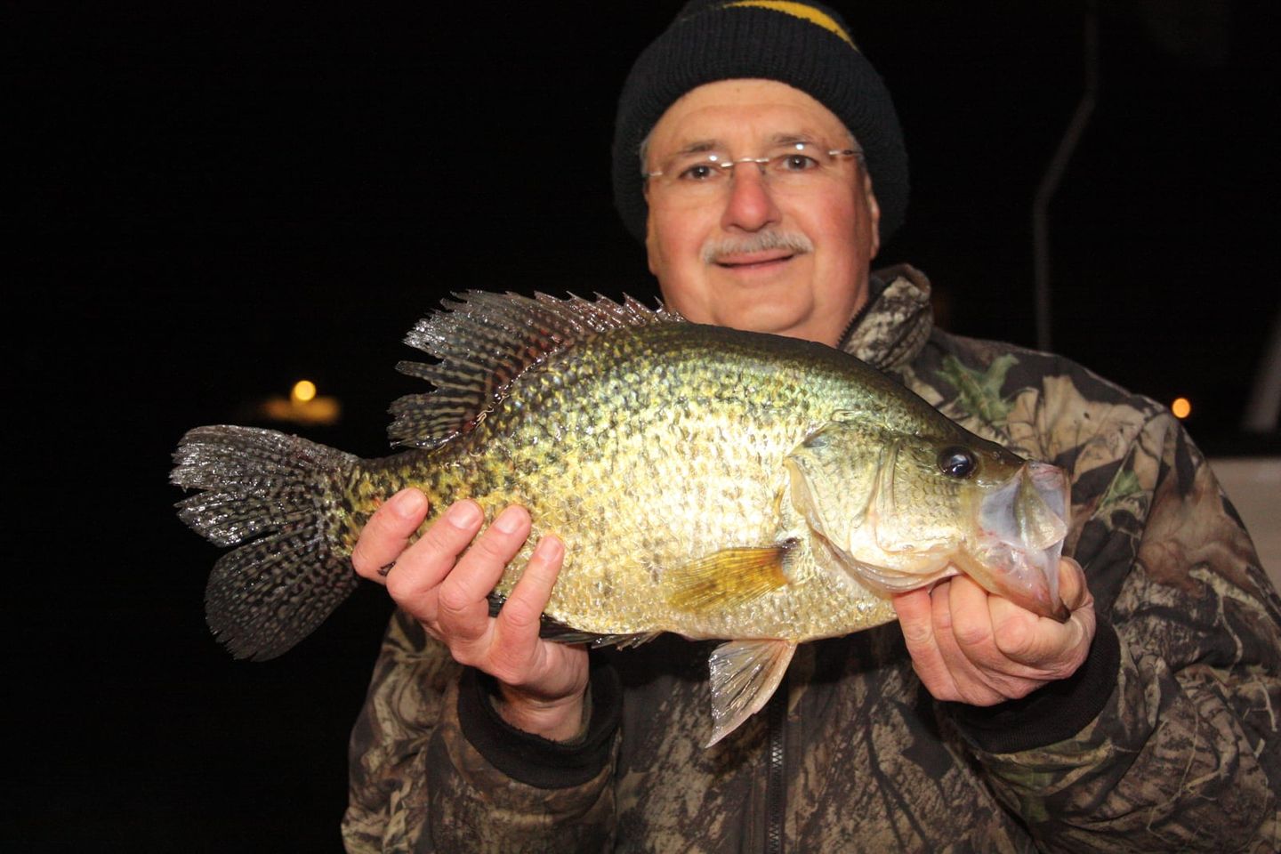 An angler holds up a large crappie.