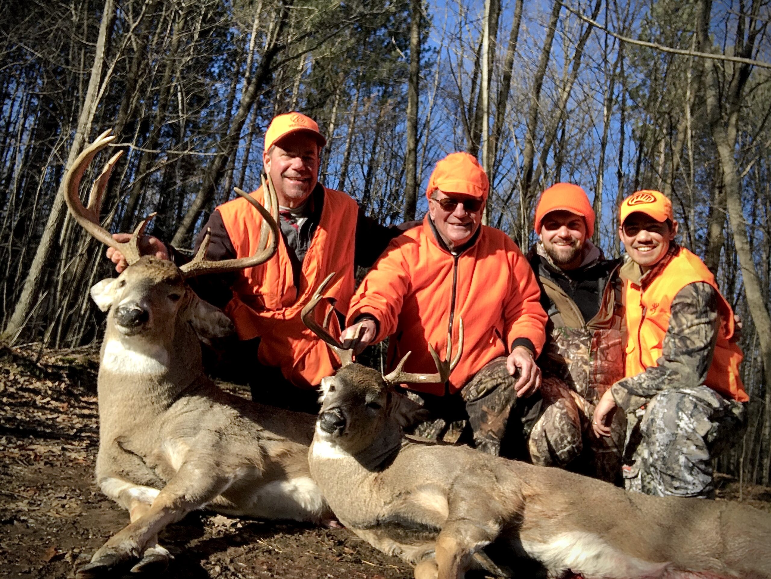 Wisconsin deer hunters in orange and camo with two mature bucks.