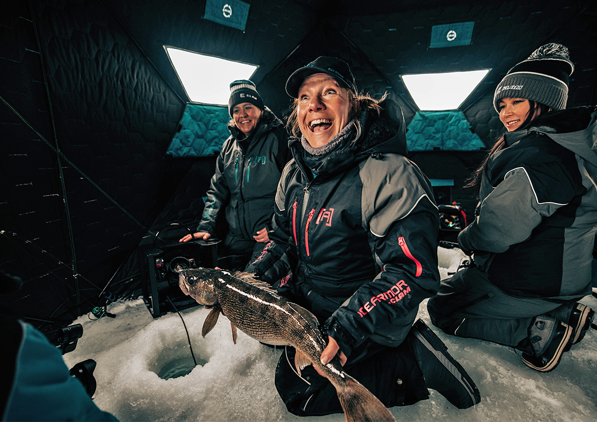 A woman catches a fish in one of the best ice fishing shelters.