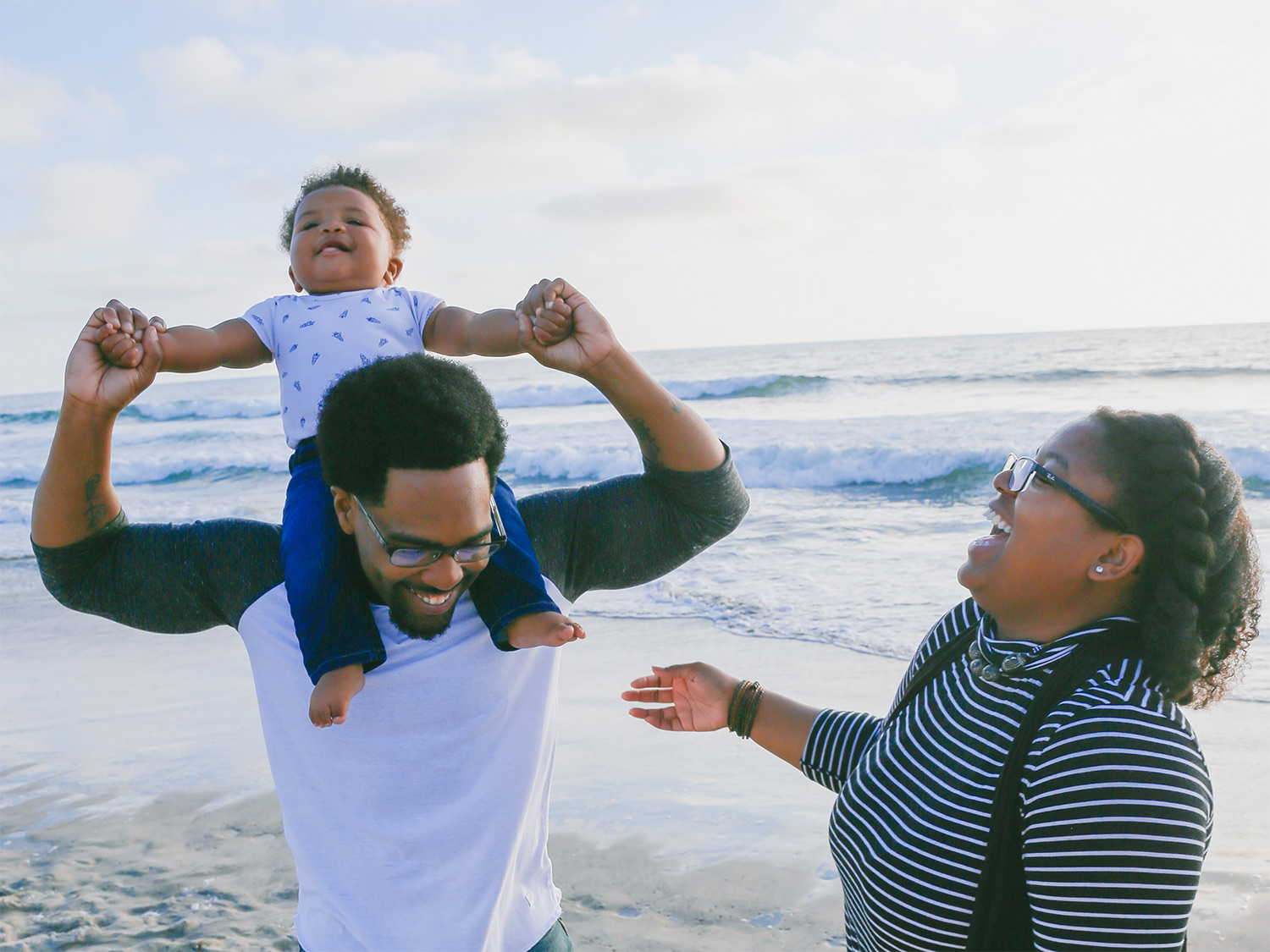 A family smiles and laughs on the beach.