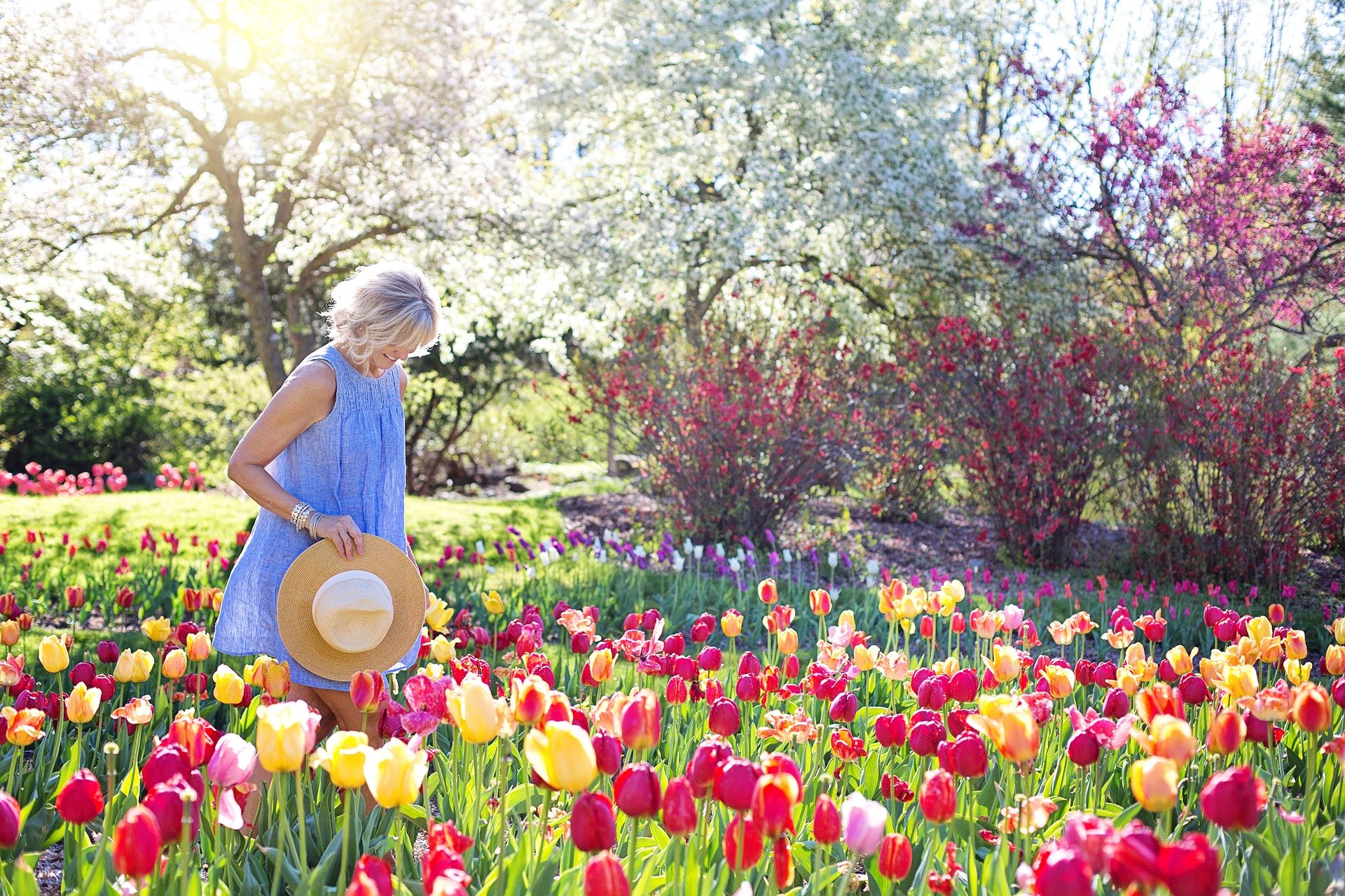 Best gifts for Mom. Woman walking through a field of flowers with a straw hat.