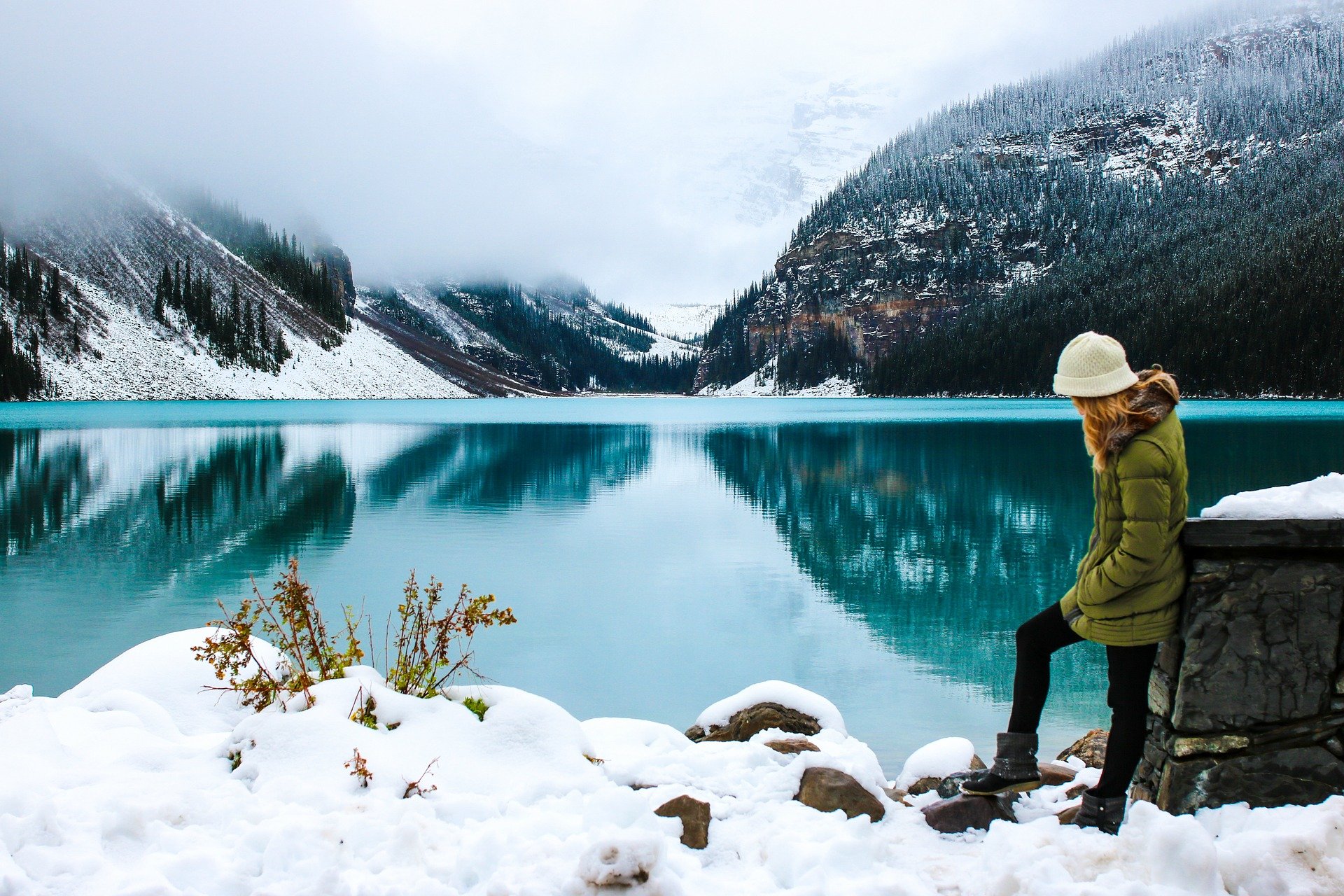 A hiker in a puffer jacket by a lake.