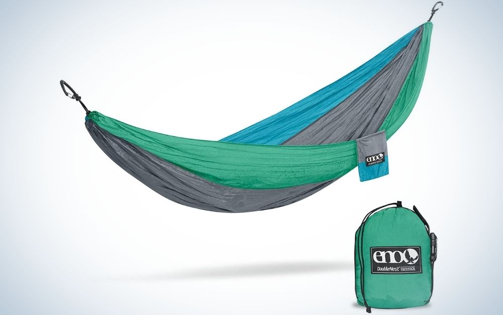 A green, blue and grey outdoor hammocks and near to it a green storage bag.