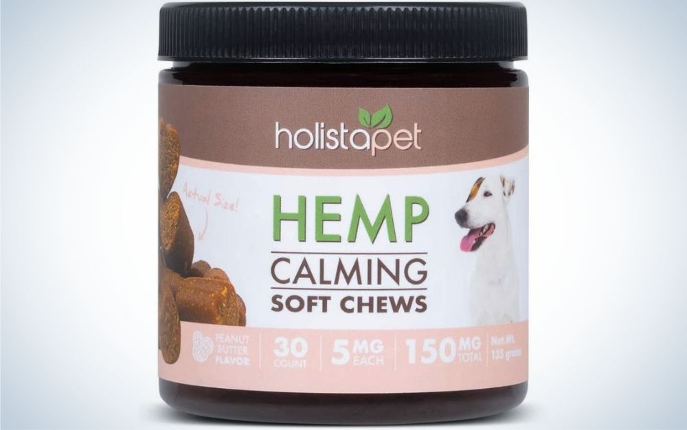 A small jar with o dog and dog food from side to side and a lettering in front of it with capita HEMP Calming soft chews.