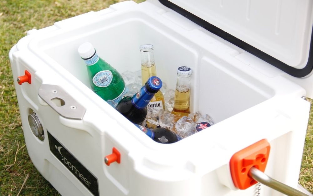 A white box cooler with different kind of drinks into it.