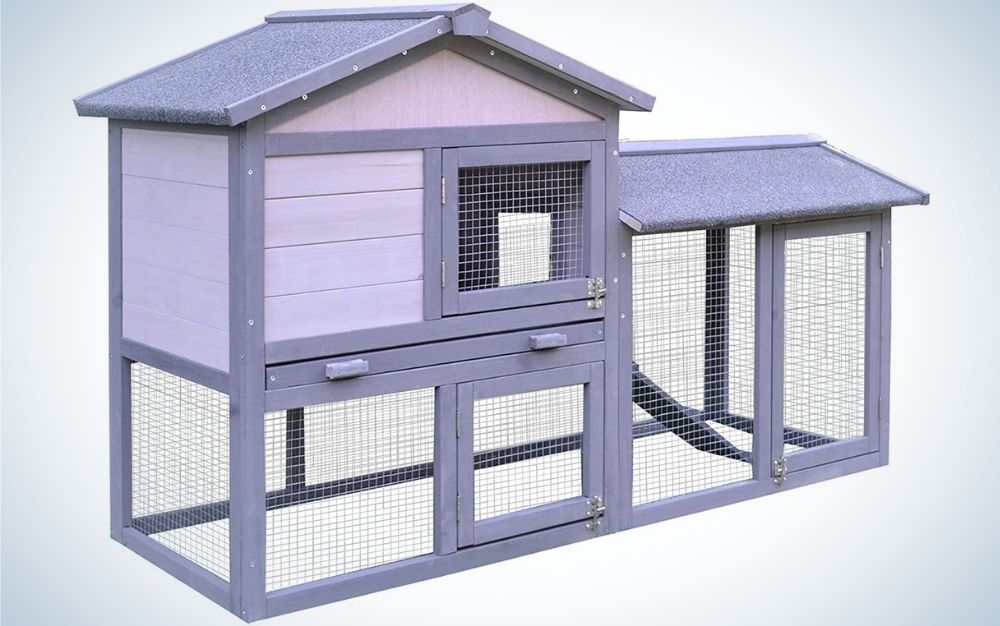 A large rabbit hutch with grey wood with a large open run area, an internal ramp and four lockable doors on the front of the hutch.