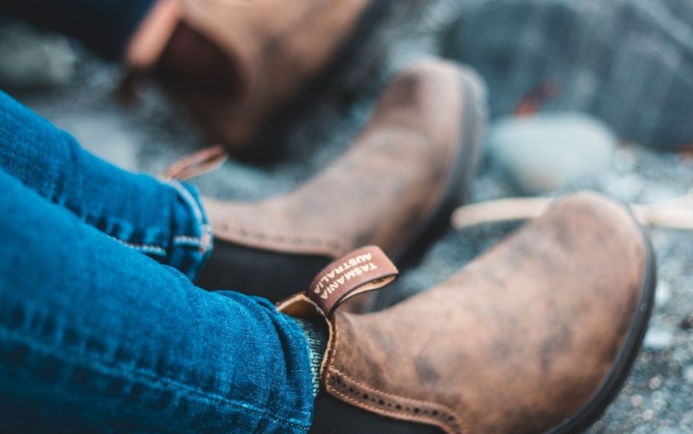 Foots of a man with jeans and with brown boots resting.