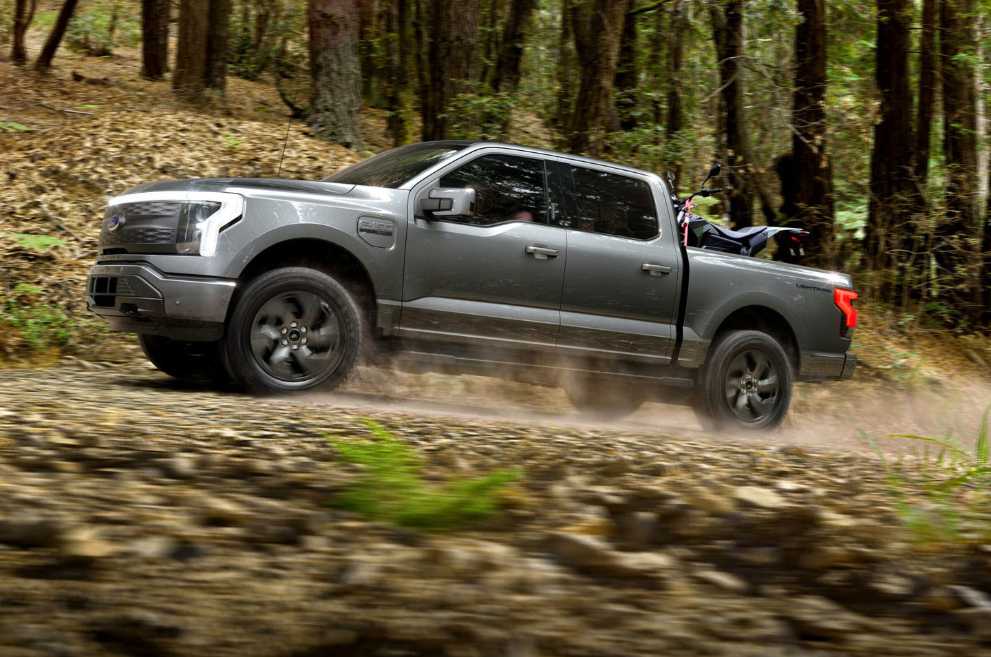 The Ford F150 lightning driving down a trail.