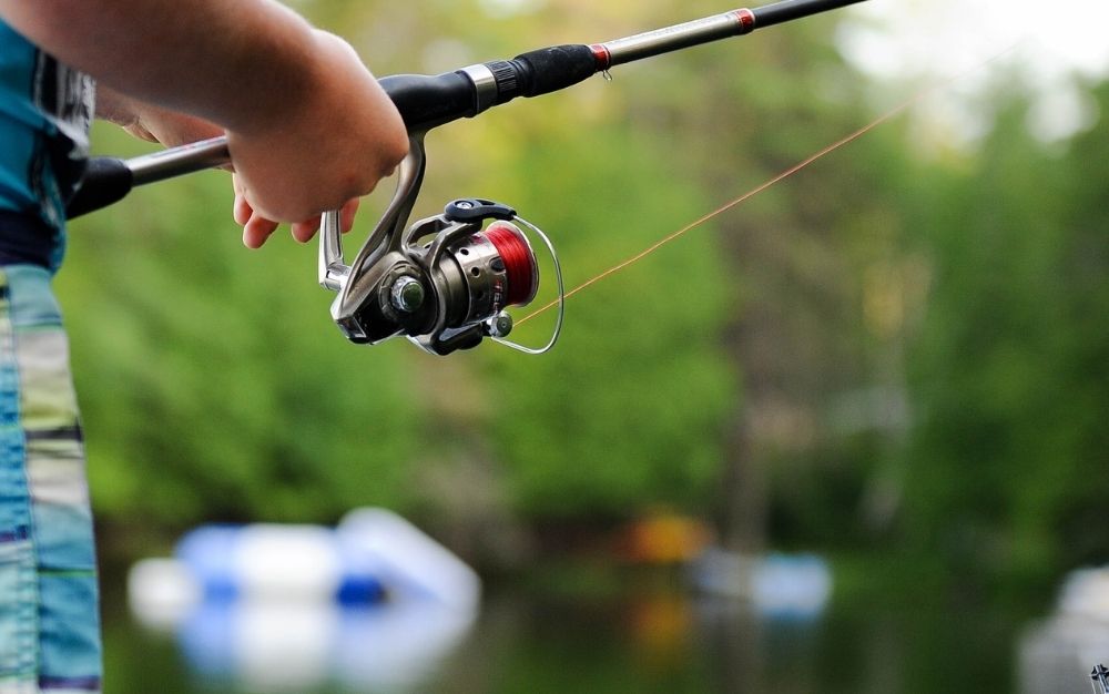 An angler turns a spinning reel.