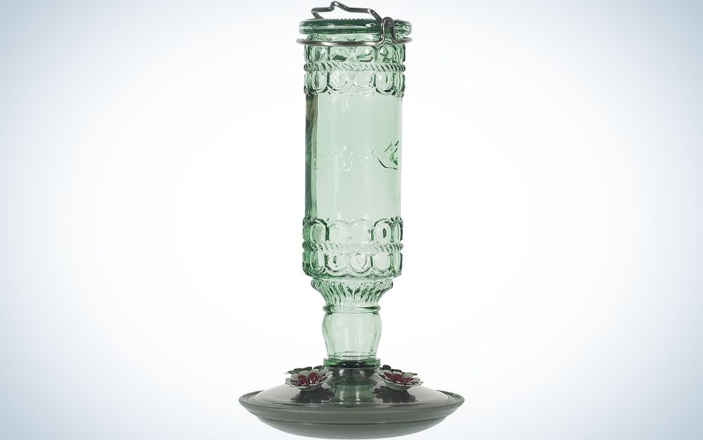 An antique glass green glass with a dark purple holder base, all of which serve to feed the birds.
