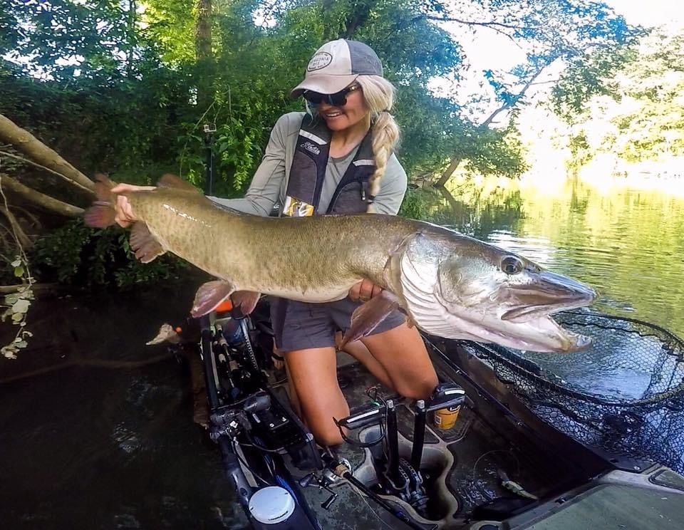 A woman on a boat holding a giant musky