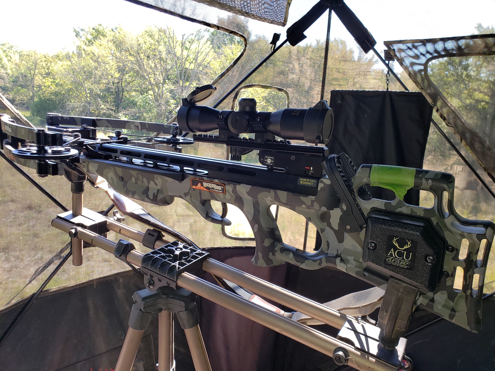 A black crossbow set up in a hunting blind