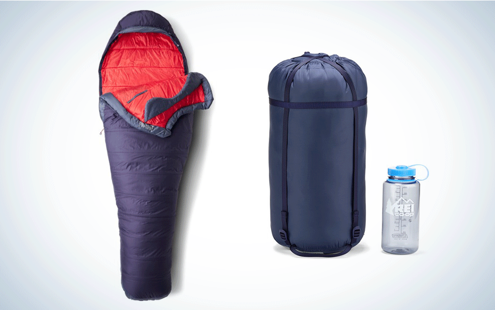 A purple and red sleeping bag next to its stuffsack and a water battle, for scale