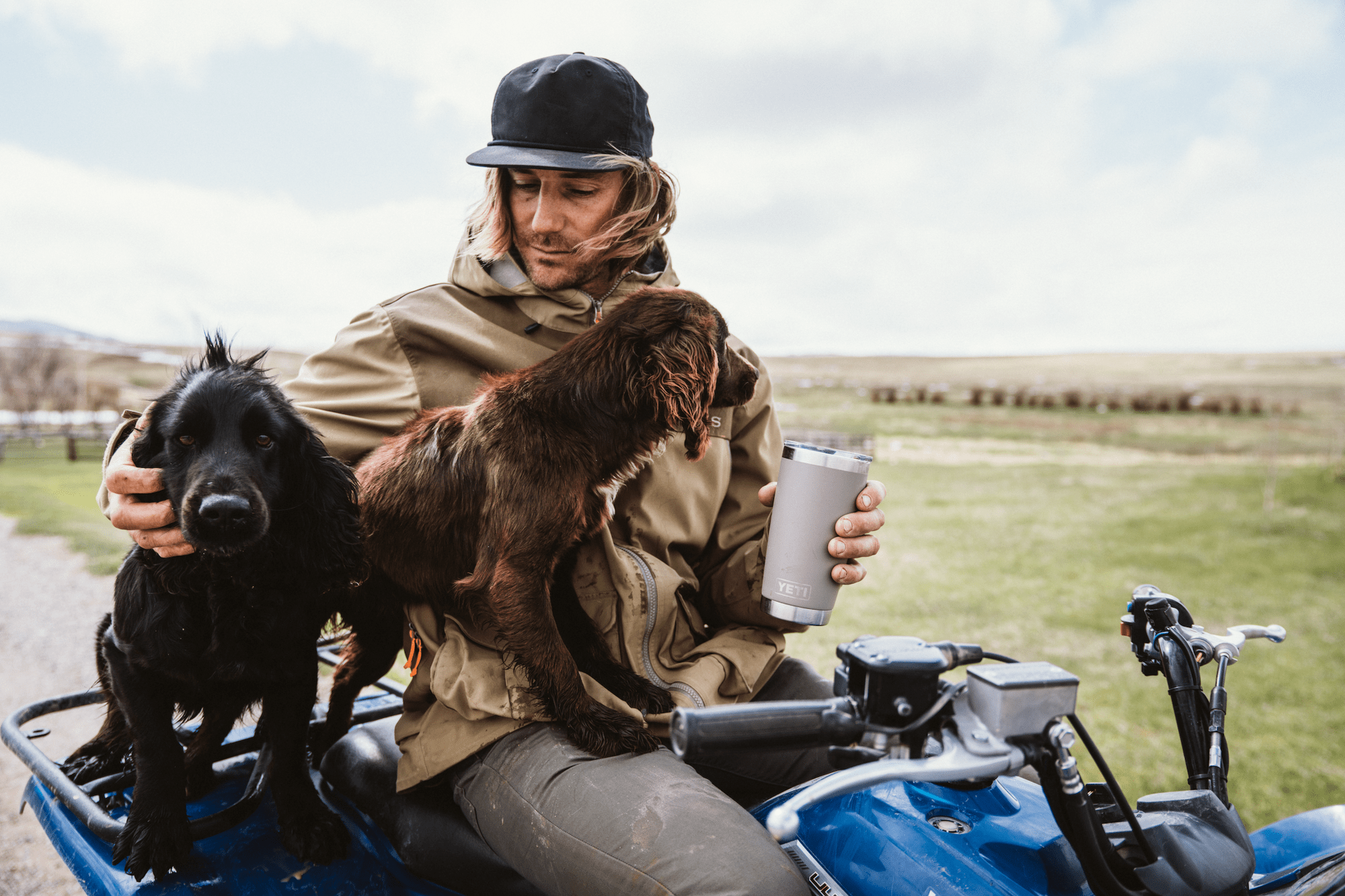A man with two dogs holding a thermos