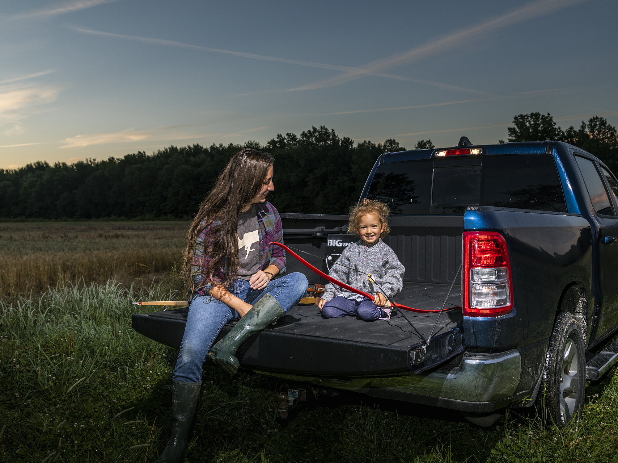 Beka Garris and her daughter sit in a pickup bed with a little Bear bow.