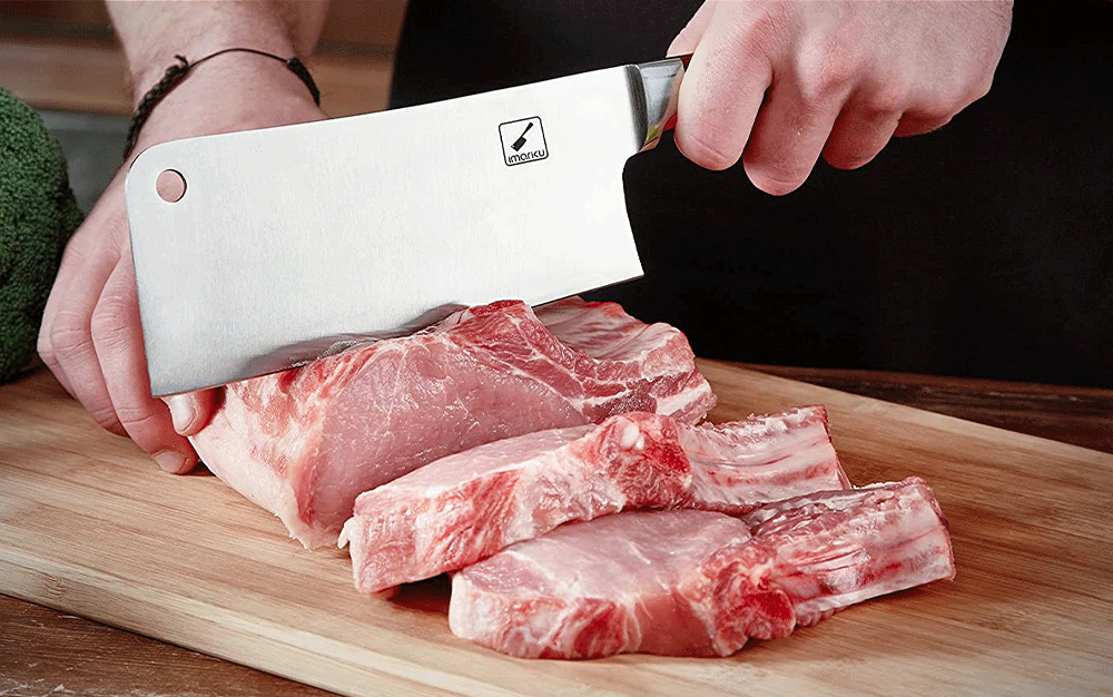 A meat cleaver used to slice raw meat on a wooden board