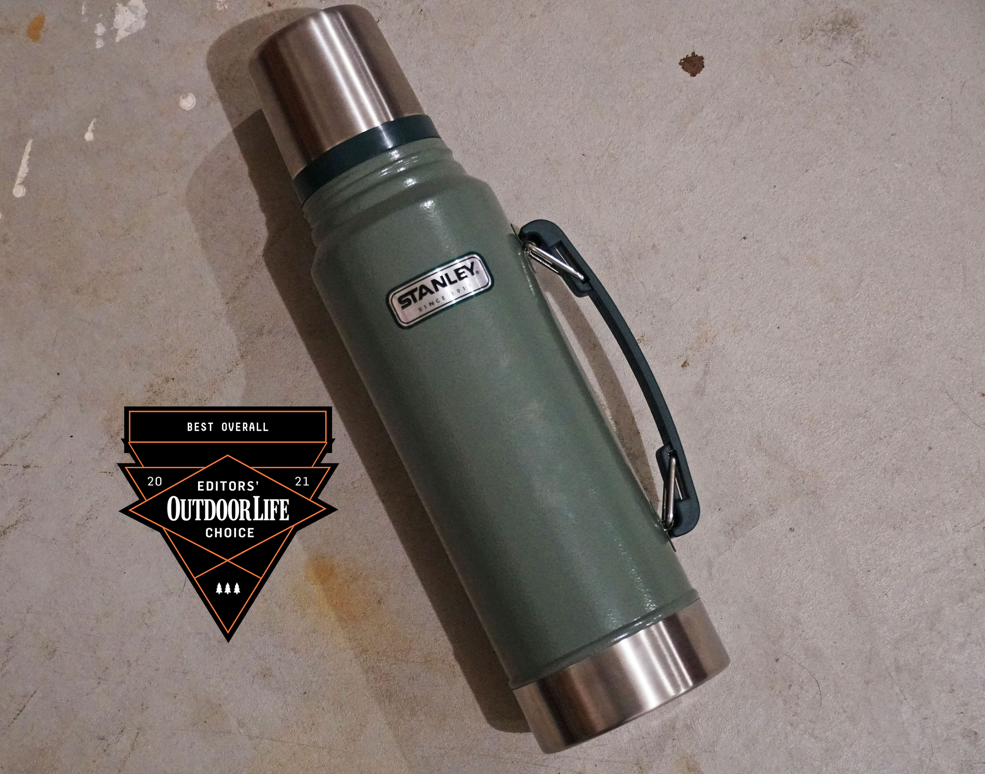 A green Stanley thermos with a handle and a silver top