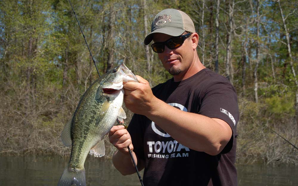 A man on the water holding a green bass