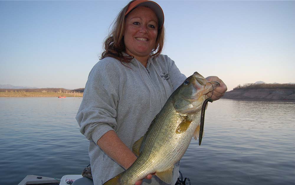 A woman on the water holding a large bass