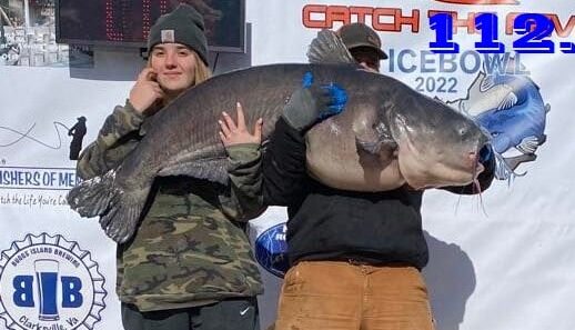 A father and daughter team hold up a 112-pound bluecatfish.