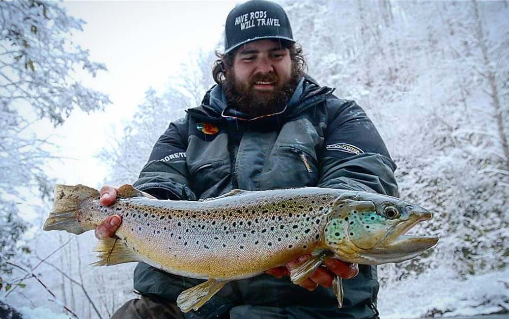 A man holding a large trout in the snow