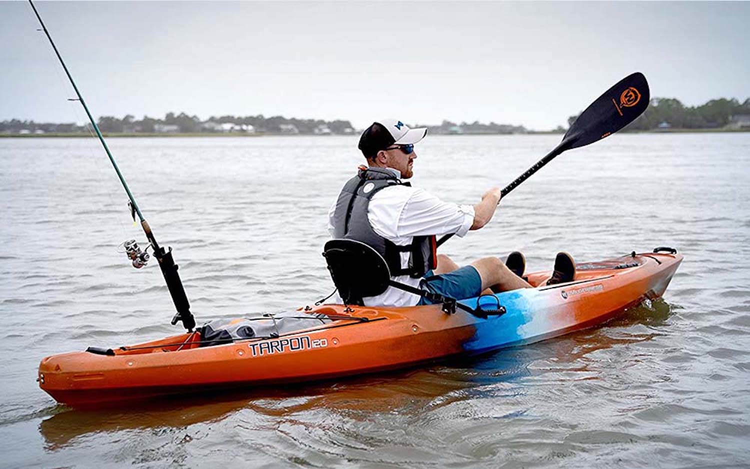 A man paddling an orange kayak