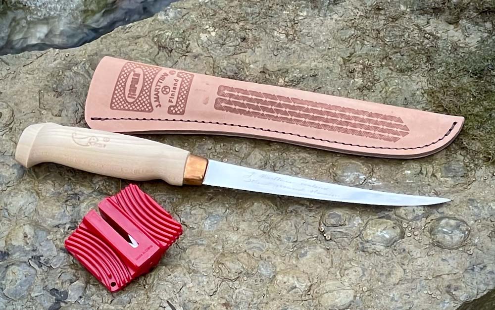 A best fillet knife with a wooden handle next to a leather sheath