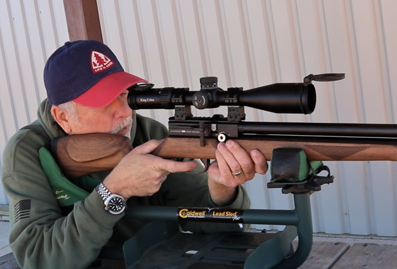 A man shooting a wooden airgun looking through a black air rifle scoppe