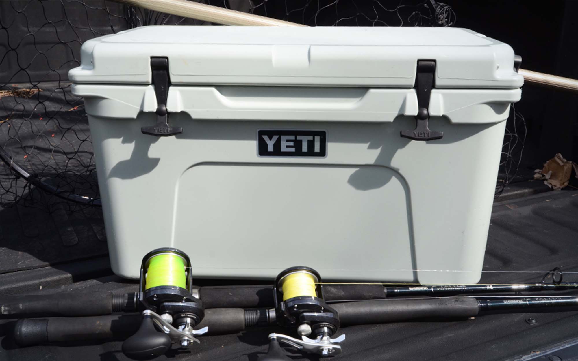 A grey best fishing cooler next to two fishing rods