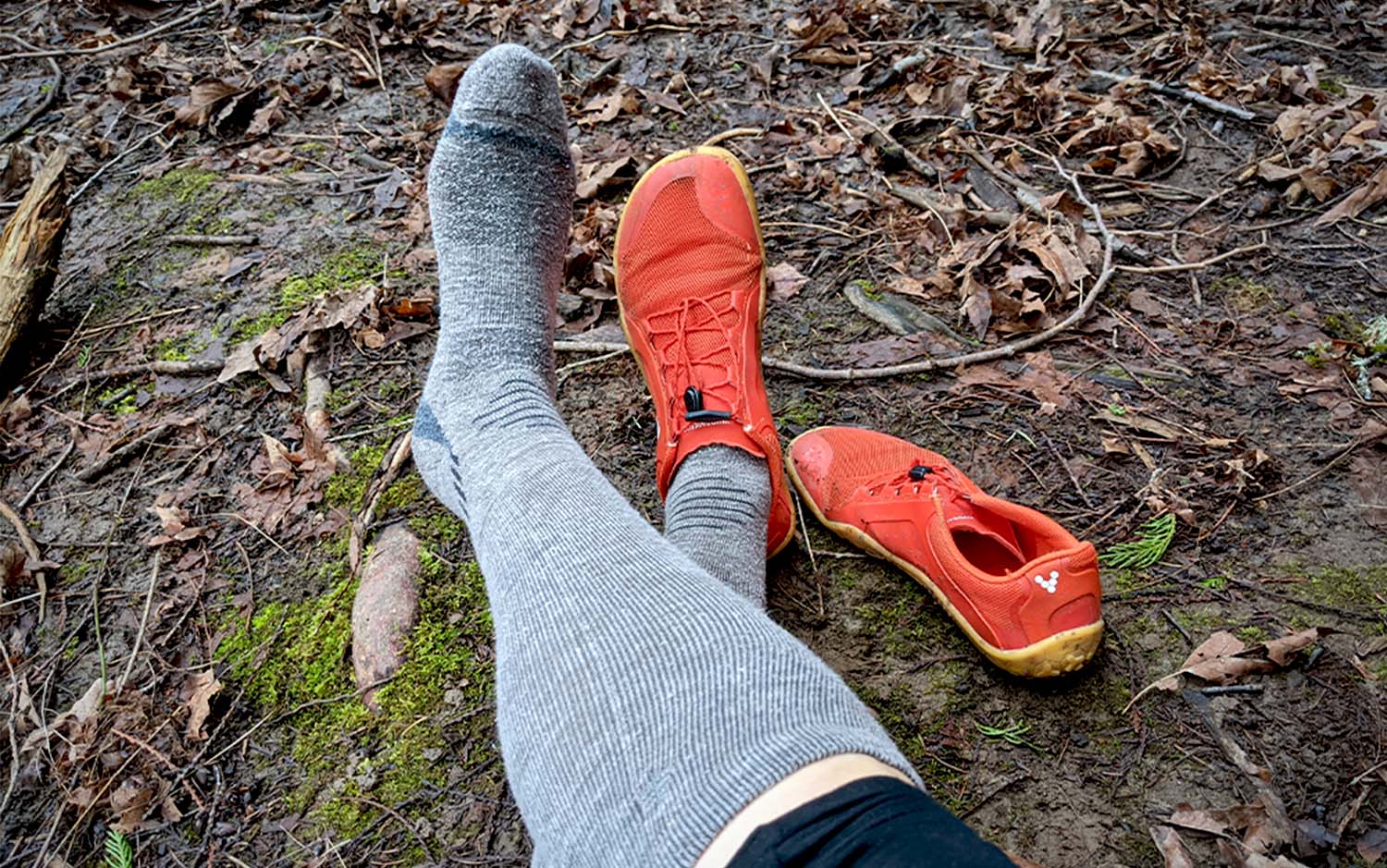 Crossed legs wearing grey hiking socks and orange hiking shoes