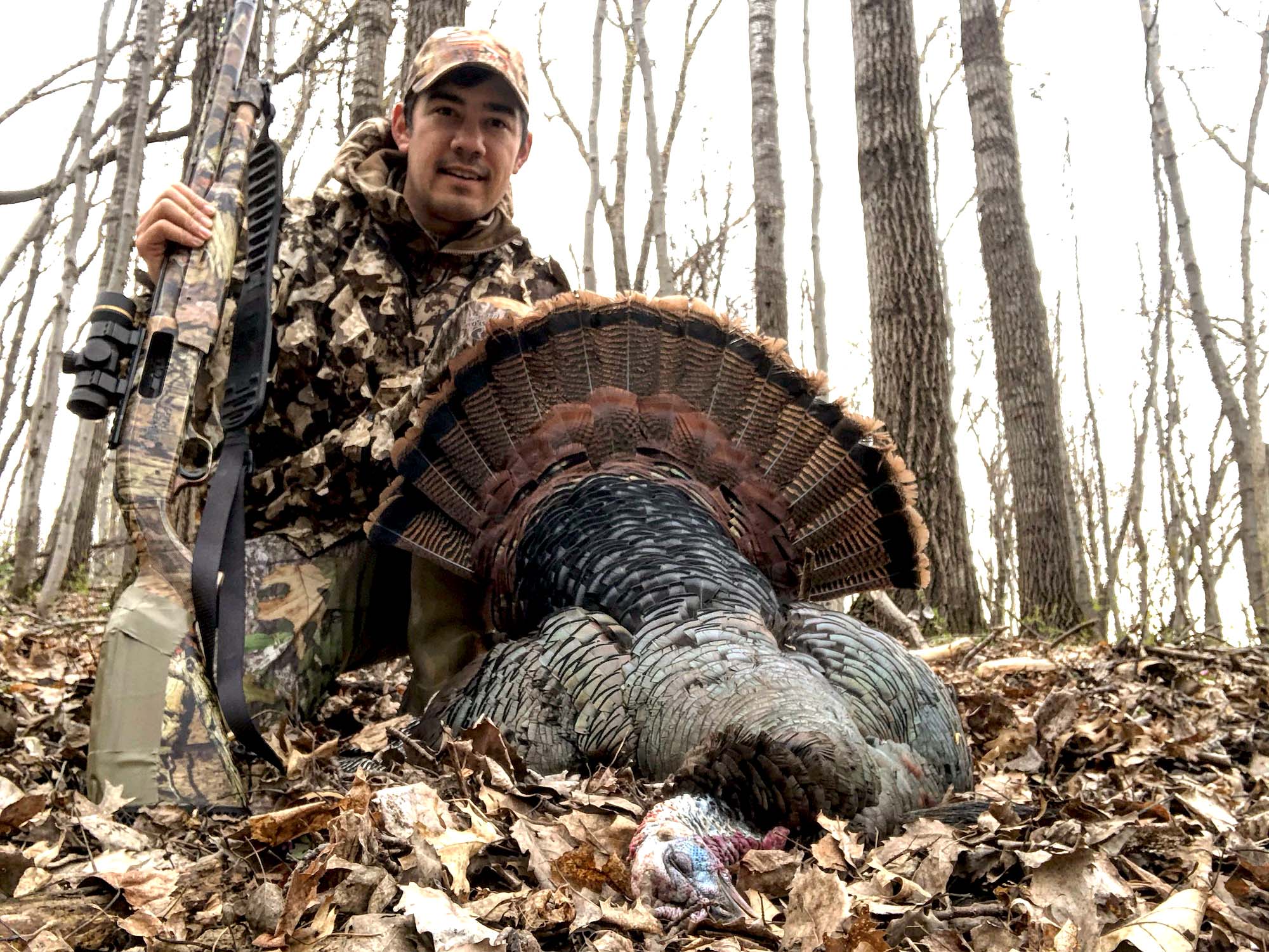 A man holding a turkey and a best turkey hunting shotgun