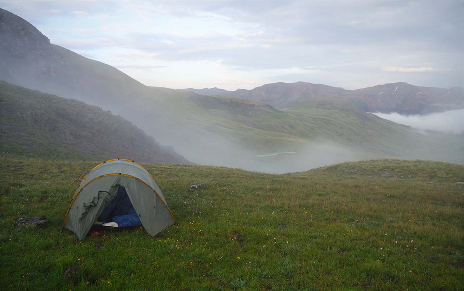 A tent in front of a misty mountainscape
