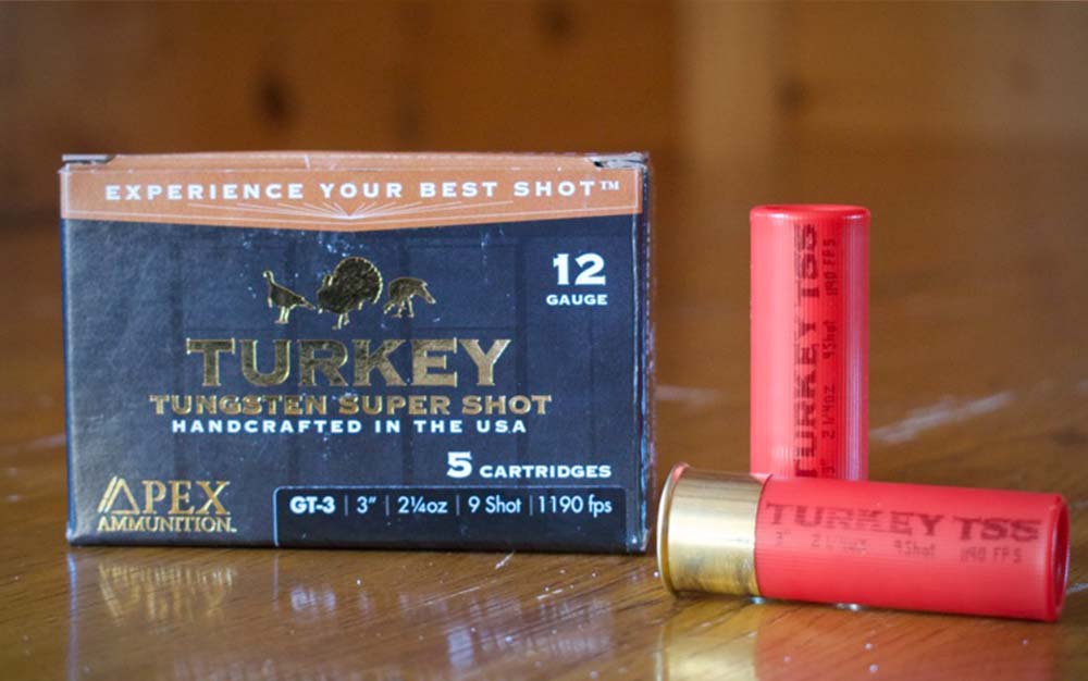 Two red shot shells next to a black box of the best turkey loads