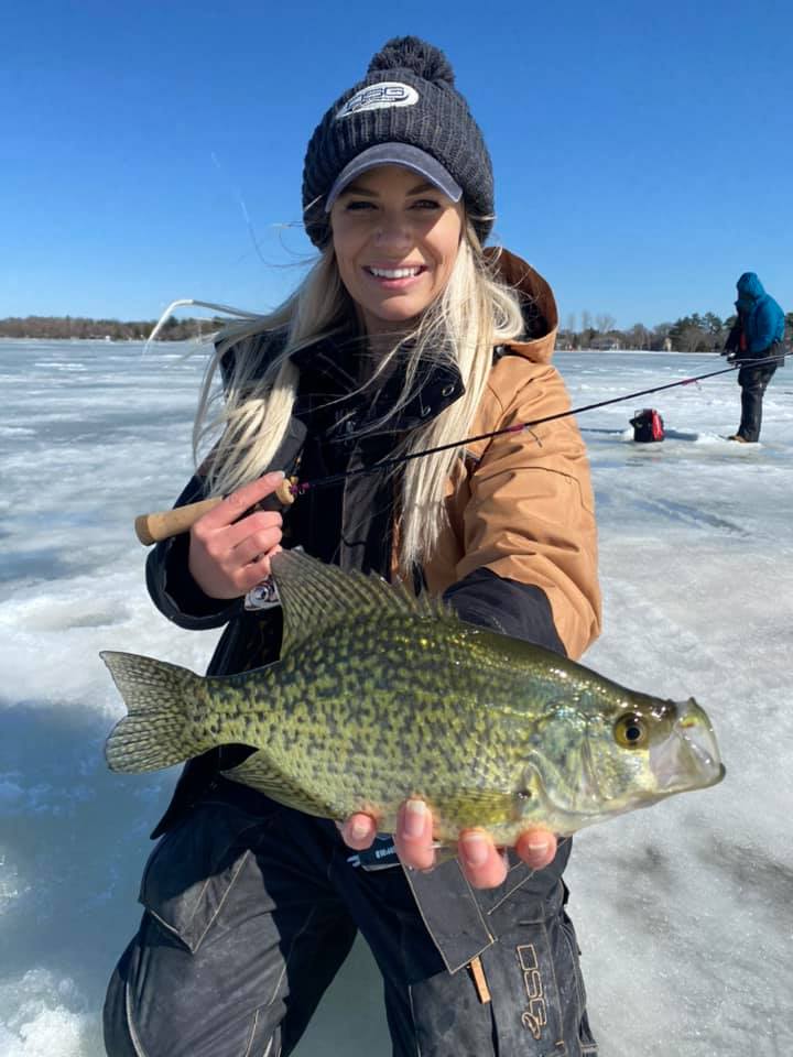 A woman holding a crappie on a frozen lake