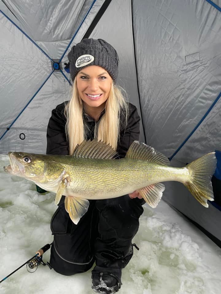 A woman in a tent holding a large walleye