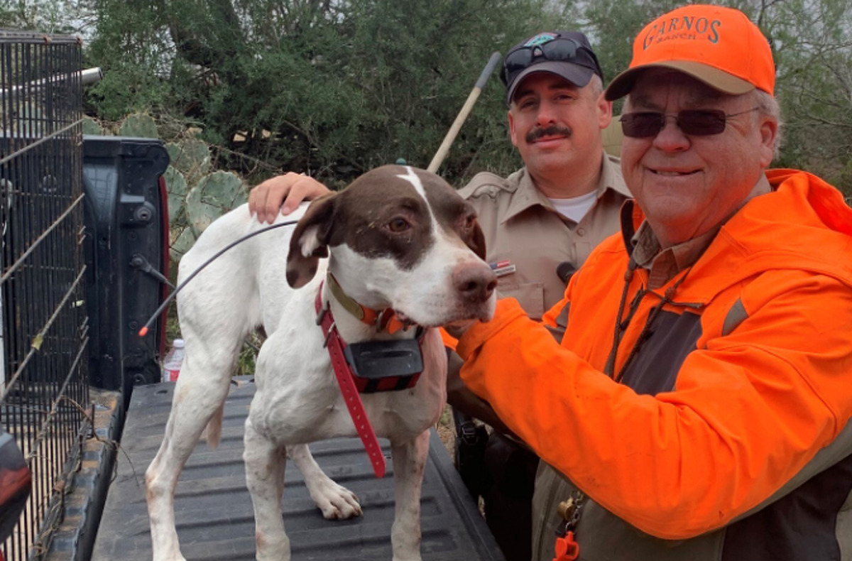 Standing next to game warden Carlos Maldonado after the rescue, Kent Key puts a loving hand on his bird dog. 
