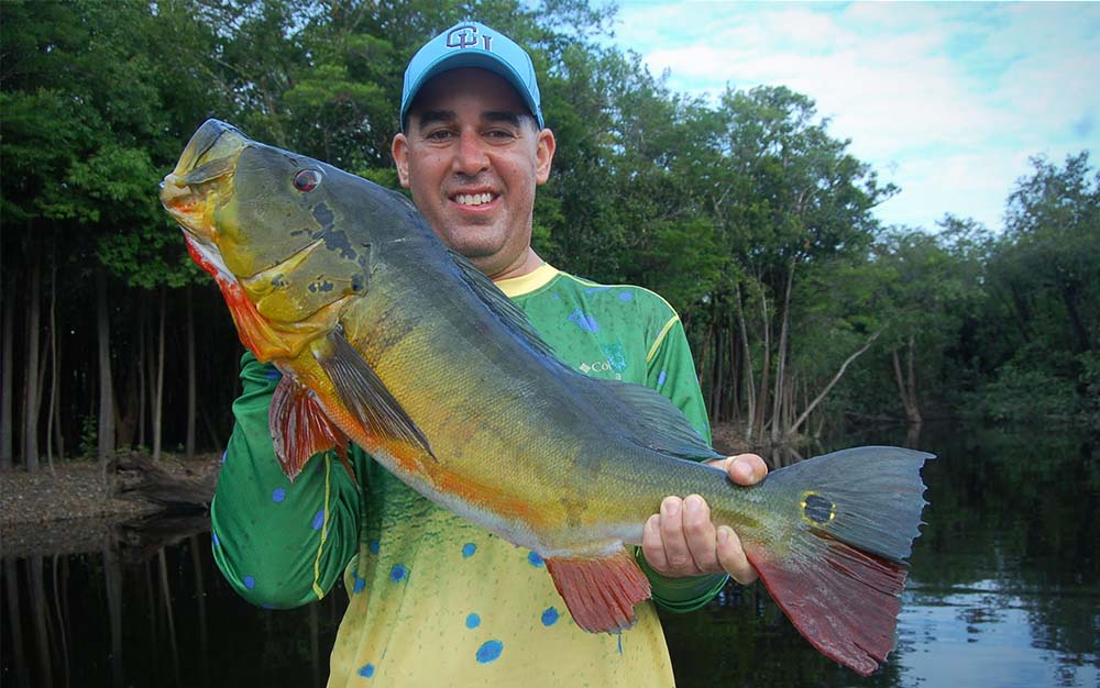 The author with a peacock bass caught on a trip to the Amazon.
