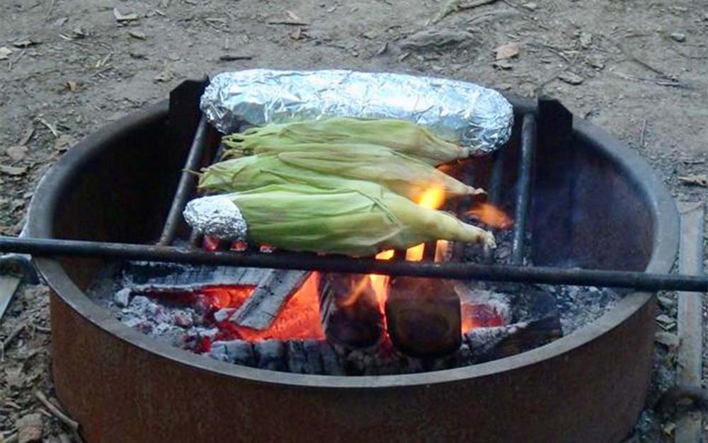 Cooking corn on the cob over an open fire is an easy camp meal.