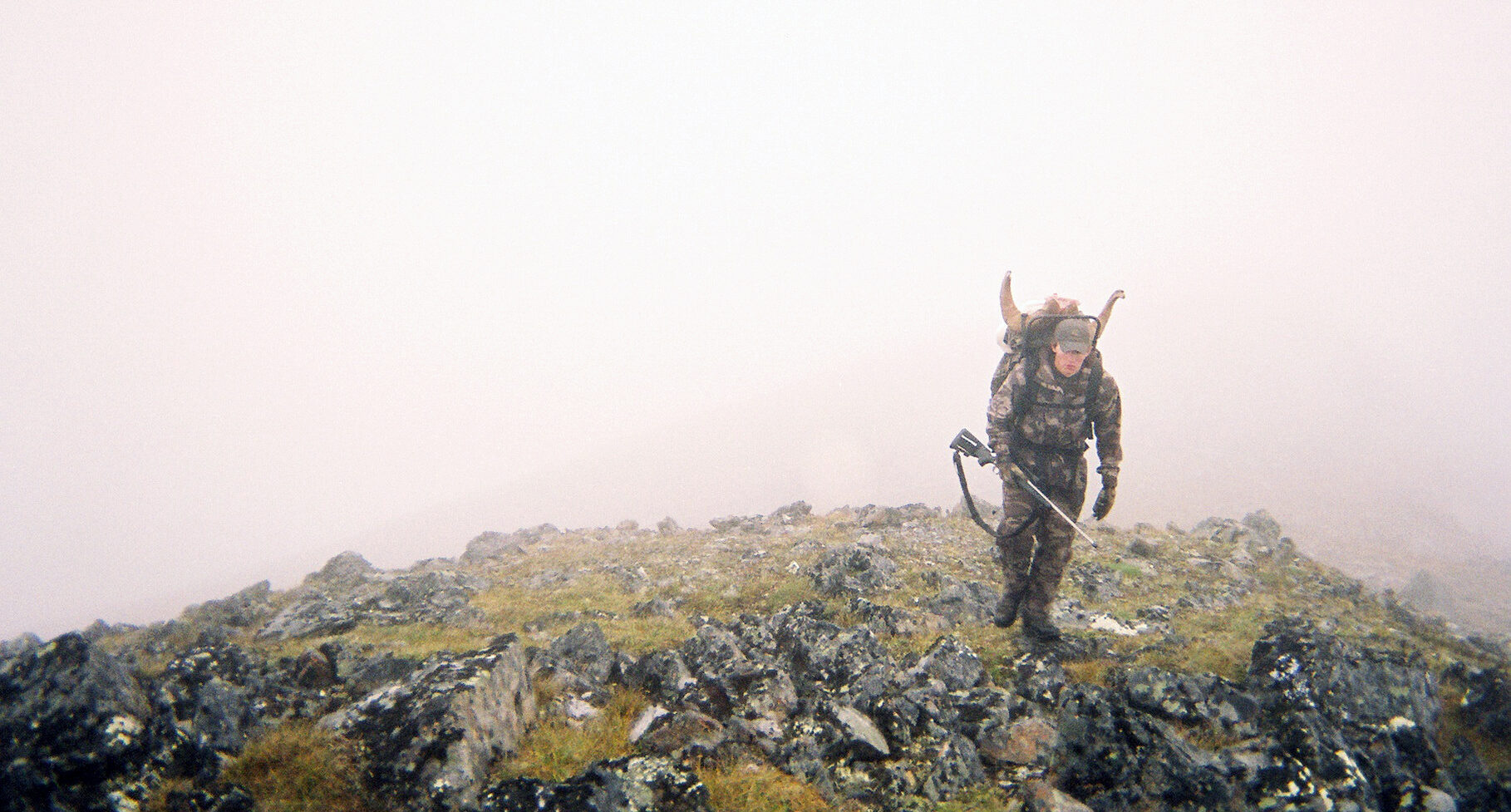 hunter crests a mountain in the fog