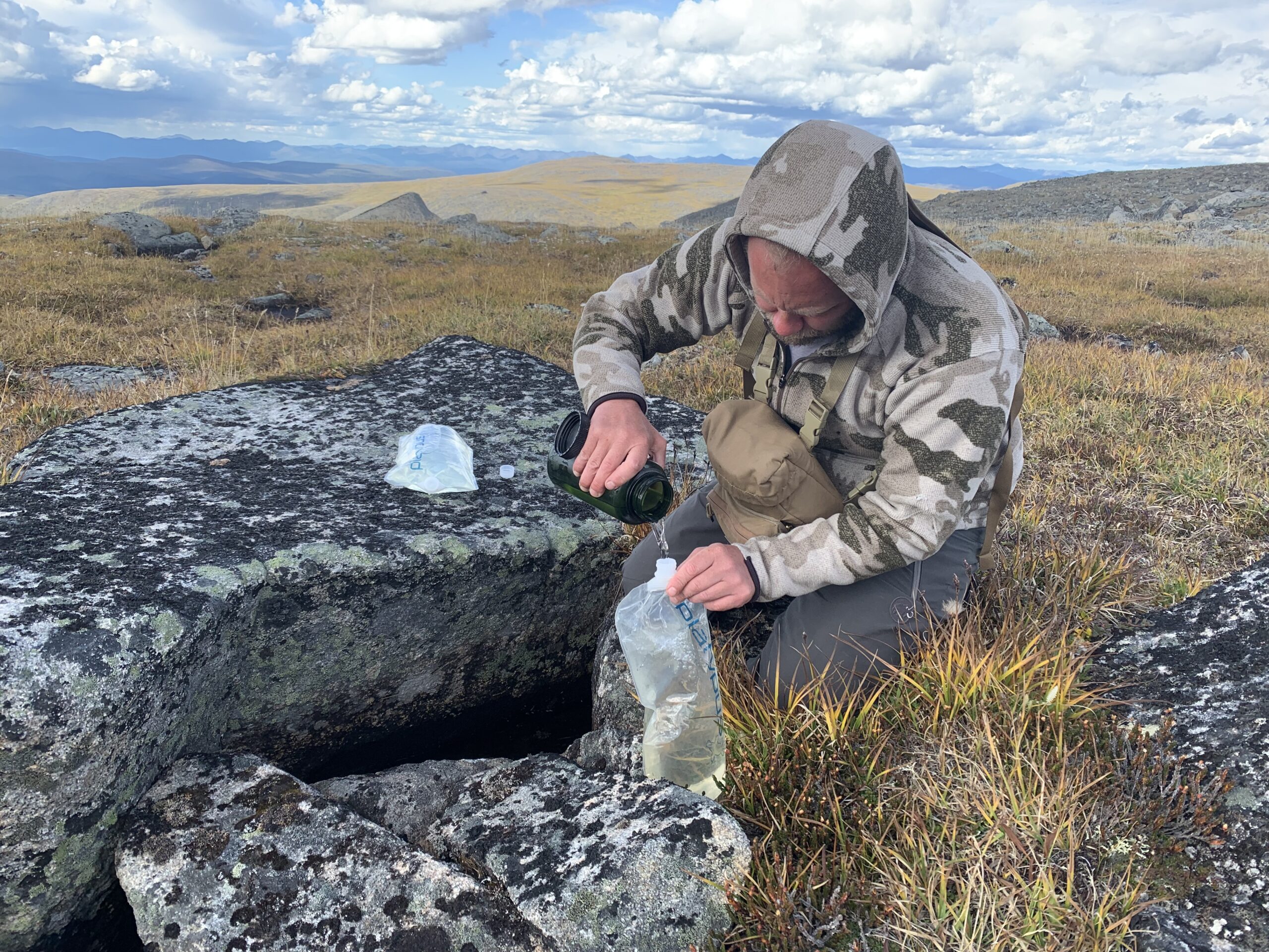 Shultz collects water from underneath a rock