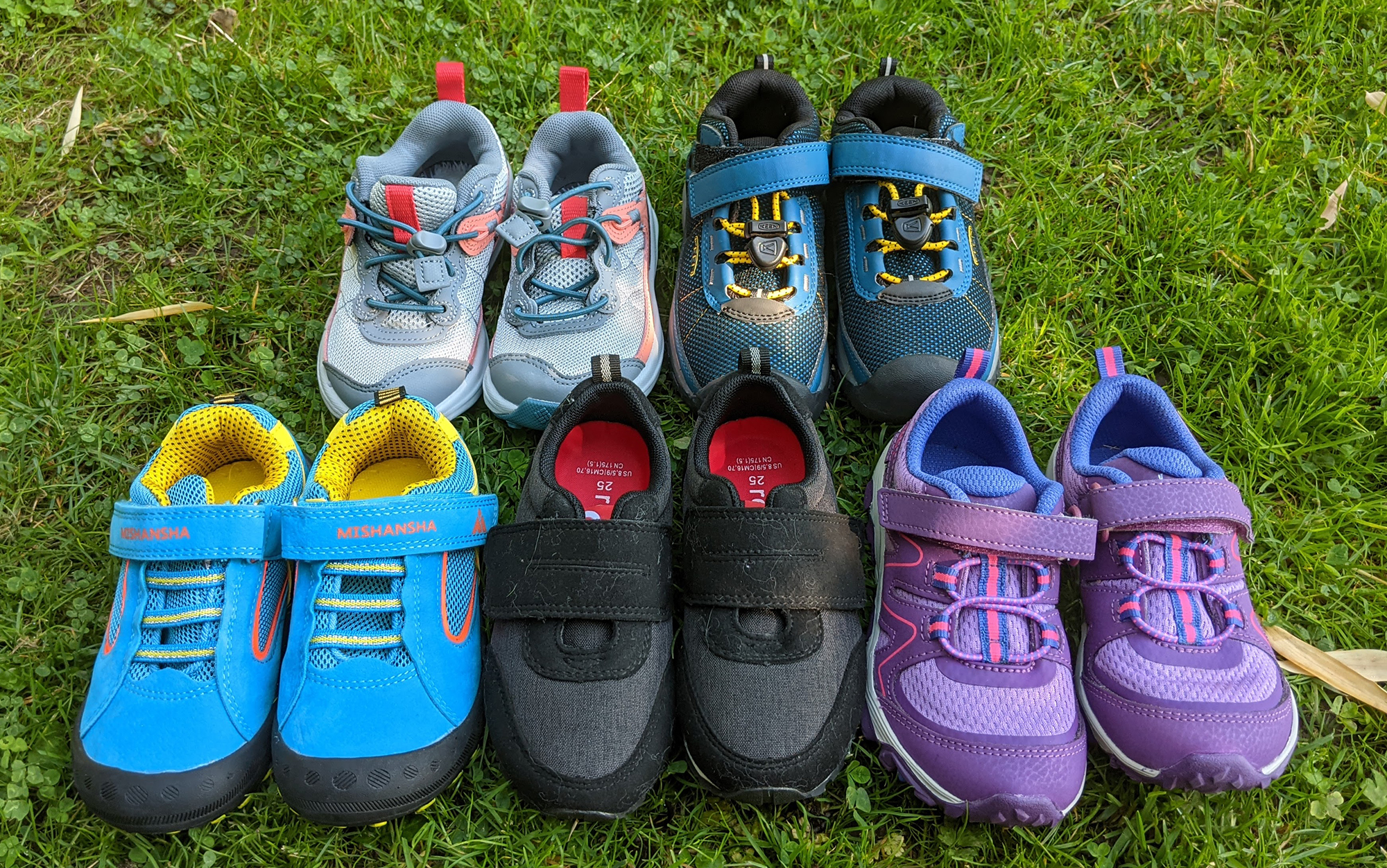 The best hiking shoes for kids lined up in the grass.
