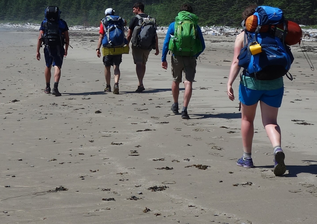 Backpacker walking on a beach.
