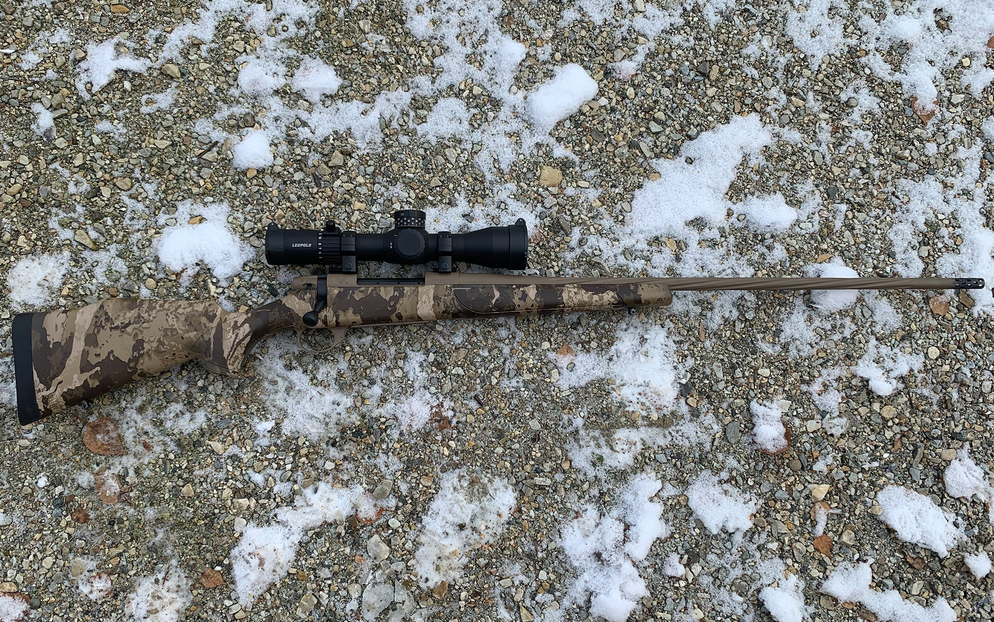 The Weatherby Vanguard First Lite laying on snowy rocks.