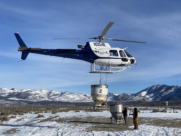 A helicopter spreads native grass seed across a landscape in eastern Nevada.
