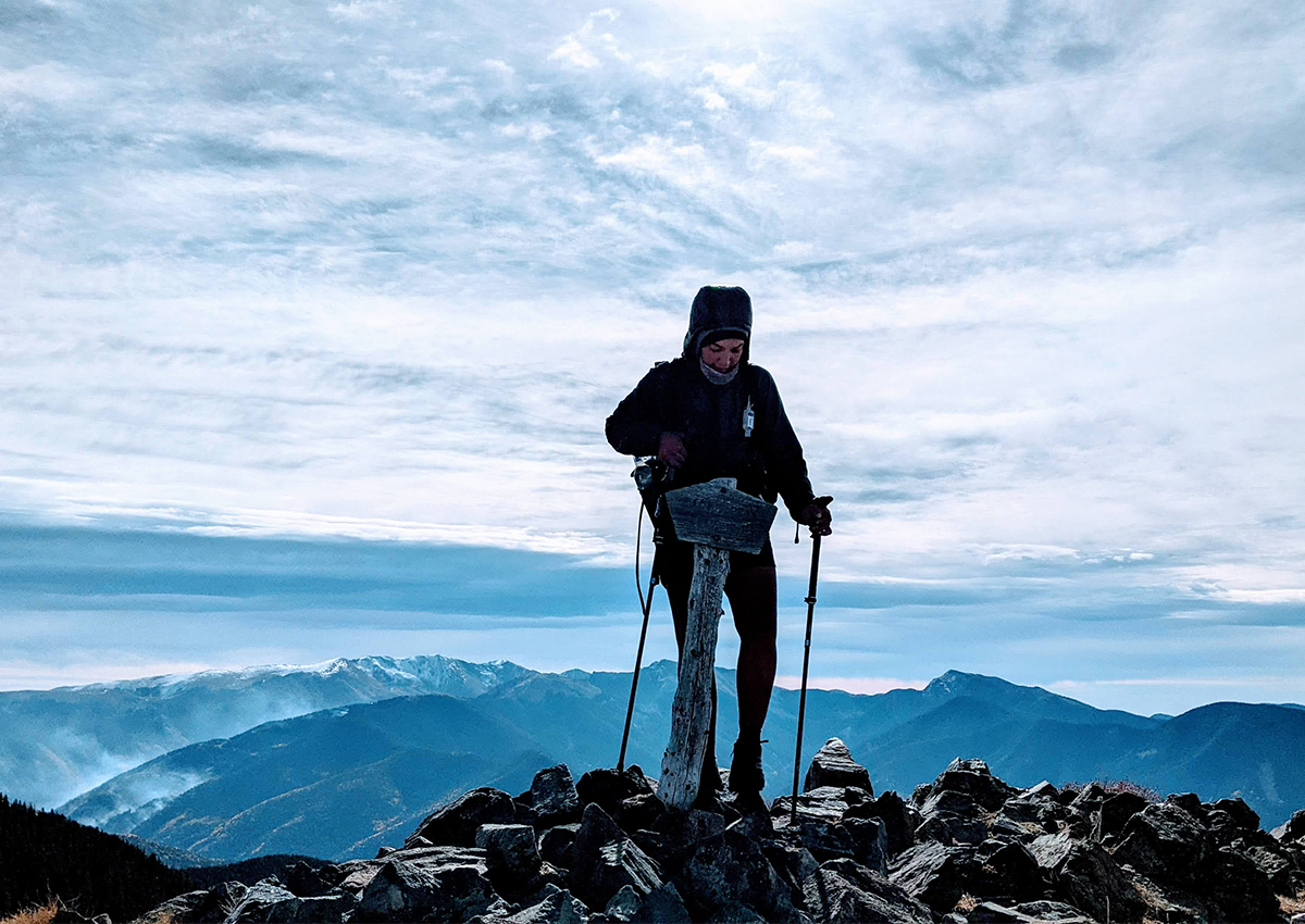 A thru-hiker stands on a ridgeline.
