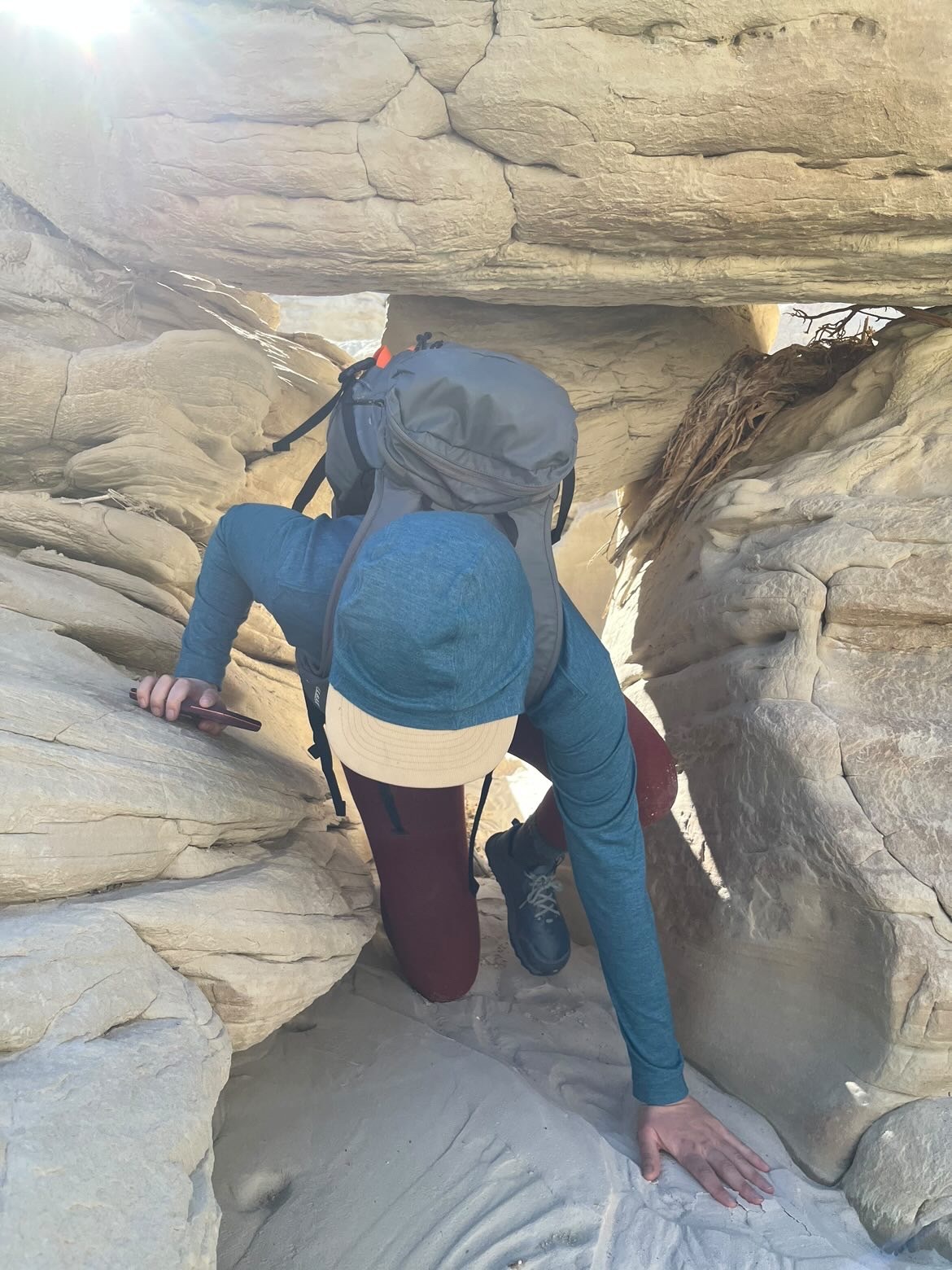 Author crawls under rock with one of the best winter backpacks.