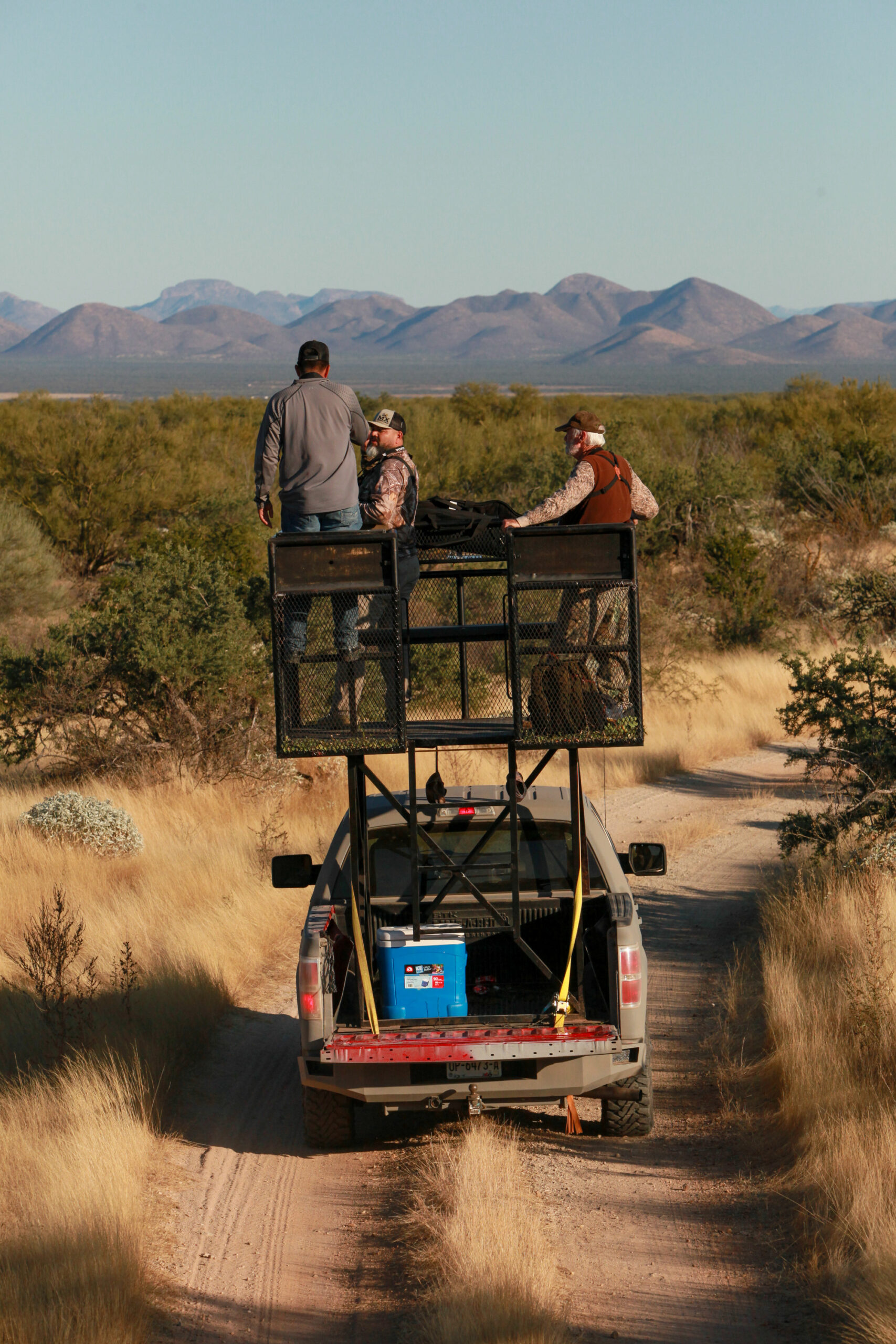 hunters stand in platform above pickup truck