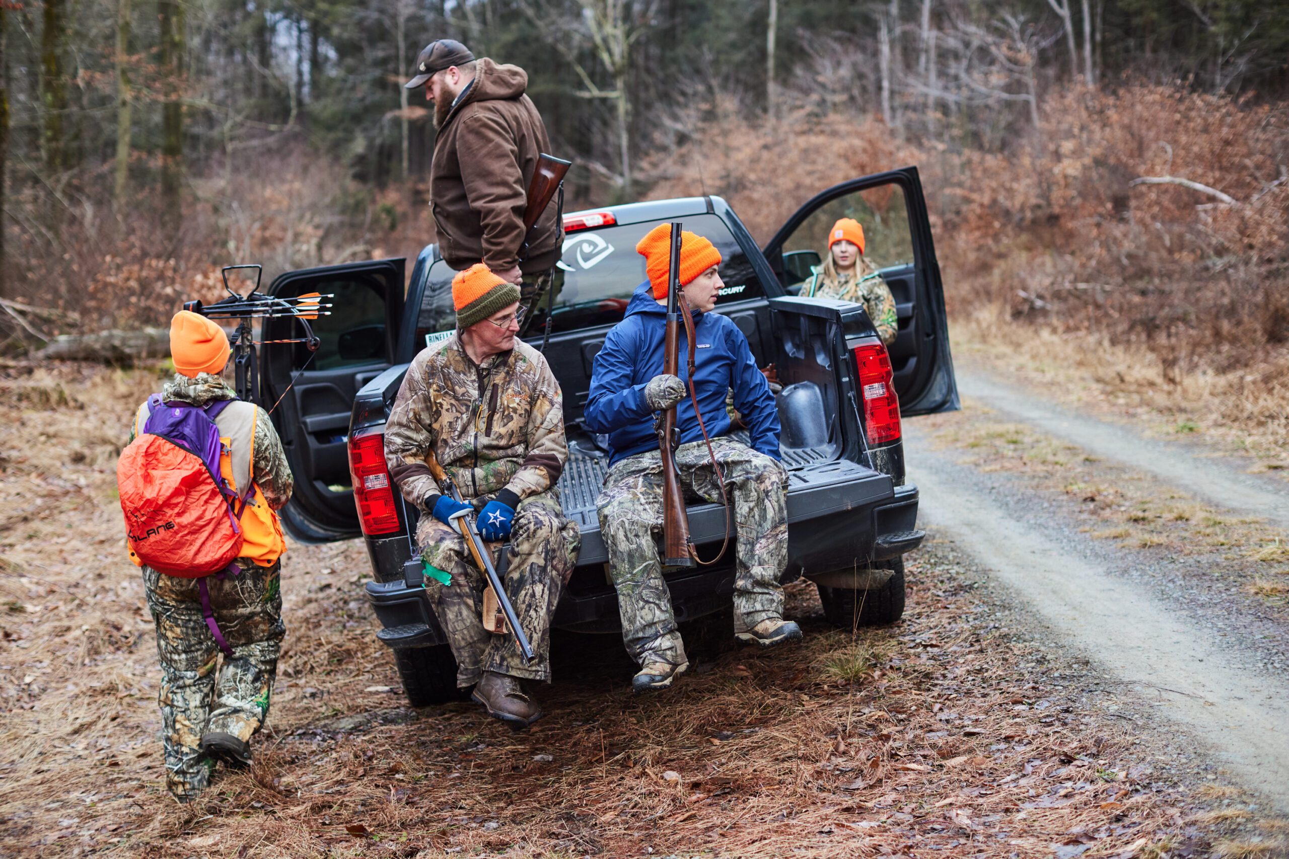 Hunters climbing into a truck and sitting on the tailgate head back to camp.