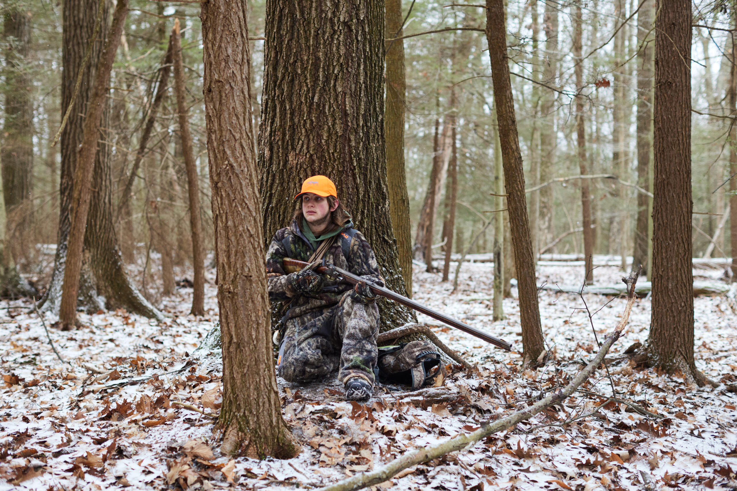 A hunter with a flintlock watches for deer in the snowy woods.