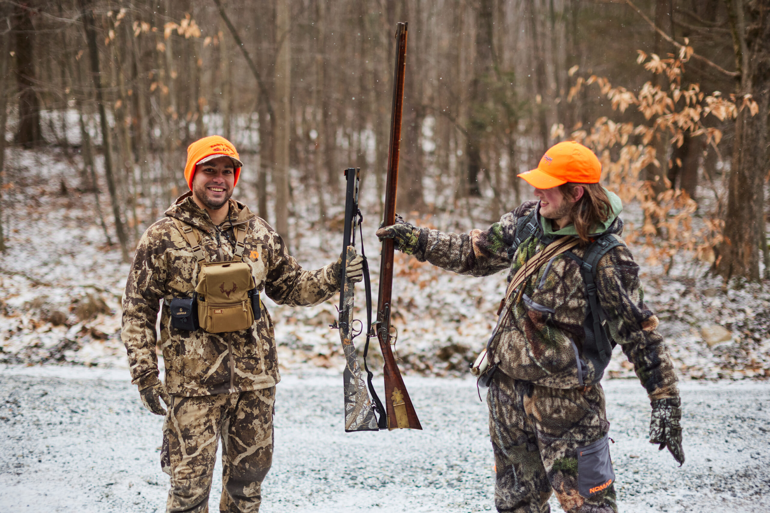 Two flintlock hunters compare rifles in the snowy woods of Pennsylvania.